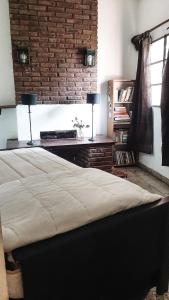 1 dormitorio con 1 cama grande y pared de ladrillo en La Esperanza en San Andrés de Giles