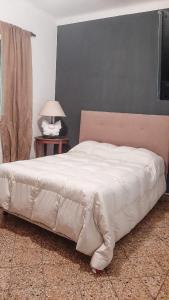1 dormitorio con cama blanca y pared gris en La Esperanza en San Andrés de Giles