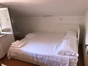 1 dormitorio con 1 cama blanca y 2 toallas en Carolina Apartments - Mansarda, en Capo dʼOrlando