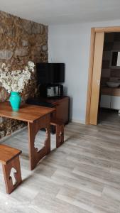 sala de estar con mesa de madera y TV en Albergue con encanto d'camiño, en Padrón