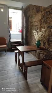 uma mesa de madeira com um vaso de flores numa parede de pedra em Albergue con encanto d'camiño em Padrón