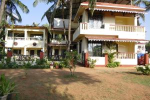 un gran edificio blanco con un patio delante en SHANU'S SEASIDE INN - A Guesthouse, 100 metres to Candolim Beach, en Candolim