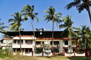 a building with palm trees in front of it at SHANU'S SEASIDE INN - A Guesthouse, 100 metres to Candolim Beach in Candolim