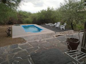 - une piscine avec une terrasse, une table et des chaises dans l'établissement TIKI HUASI, à Cabra Corral