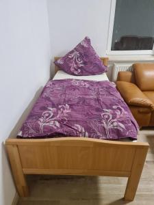 a bed with a purple blanket and a couch at GSS18 2-OG Möbilierte Wohnung in Oebisfelde in Oebisfelde