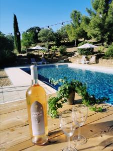 una bottiglia di vino seduta su un tavolo accanto a due bicchieri di vino di Villa Fourmaux a Néffiès