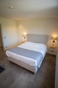 um quarto com uma grande cama branca e 2 candeeiros em Vakantiewoning De Machuut em Lo-Reninge