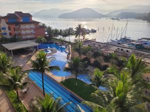 - une vue sur un complexe avec des palmiers et une étendue d'eau dans l'établissement Apart Hotel Mont Blanc Itacuruçá, à Mangaratiba