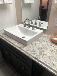 un bancone del bagno con lavandino bianco e specchio di Antelope Hills Inn a Prescott