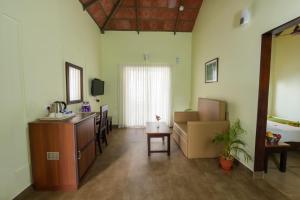 eine Küche und ein Wohnzimmer mit einem Waschbecken und einem Tisch in der Unterkunft Abad Brookside Wayanad in Vythiri