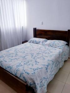 Schlafzimmer mit einem Bett mit einer blauen und weißen Bettdecke in der Unterkunft Apartamento amoblado en La Tebaida, Quindio in La Tebaida