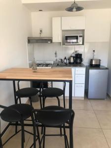 cocina con mesa de madera y sillas negras en Villa Ober Suites en Neuquén