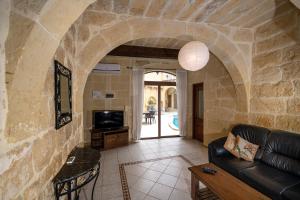 a living room with a black leather couch and a tv at Ta Gorga Holiday Farmhouse with Private Pool in Xewkija