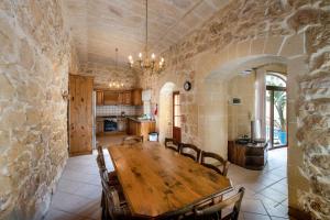 a dining room with a wooden table and a stone wall at Ta Gorga Holiday Farmhouse with Private Pool in Xewkija