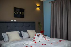 a bed with a white blanket with red roses on it at Piano & Gold Collections, Peduase in Peduasi
