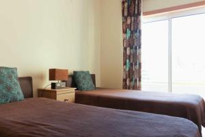 ein Schlafzimmer mit zwei Betten und einem Fenster in der Unterkunft Apartamento Maresia T2 Penthouse by Your Home Algarve in Cabanas de Tavira + 8 Fotos