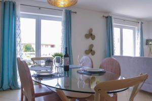 una sala da pranzo con tavolo in vetro e sedie di Apartamento AzulMar Cabanas Gardens by Your Home Algarve a Armação da Abóbora
