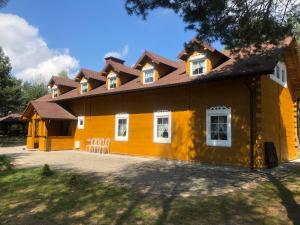 a yellow house with white windows and a roof at Dolina Bobrów in Siennica