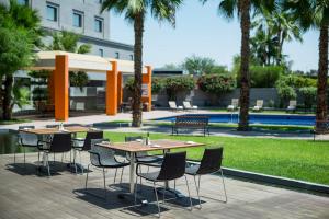 a group of tables and chairs in a courtyard with palm trees at Real Inn Mexicali in Mexicali