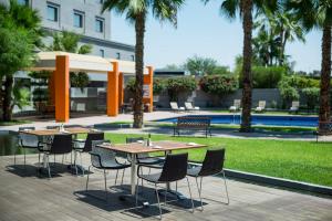 - un groupe de tables et de chaises dans une cour avec des palmiers dans l'établissement Real Inn Mexicali, à Mexicali