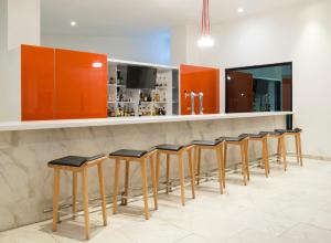 a row of stools at a bar with orange cabinets at Real Inn Mexicali in Mexicali
