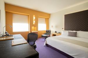 ein Hotelzimmer mit einem großen Bett und einem Schreibtisch in der Unterkunft Camino Real Monterrey in Monterrey