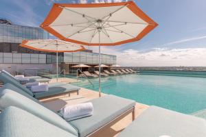 a swimming pool with chairs and an umbrella at Camino Real Mérida in Mérida