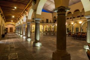 an arcade with columns in a building with tables at Quinta Real Puebla in Puebla