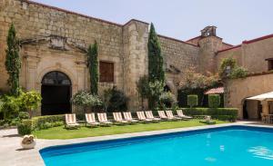 a pool in front of a building with lounge chairs at Quinta Real Oaxaca in Oaxaca City