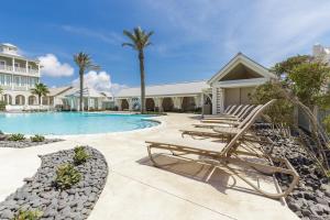 a swimming pool with lounge chairs next to a house at Sleek Beach at Palmilla Beach in Port Aransas