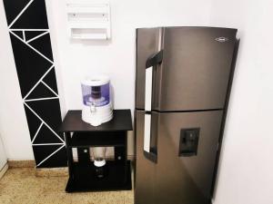 a stainless steel refrigerator with a coffee maker on a stand at Hermoso apartamento en el centro histórico de San Gil I 2 in San Gil