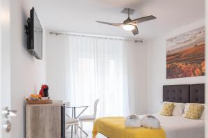 a bedroom with two beds and a table and a ceiling fan at Hostal Puente de Hierro in Logroño