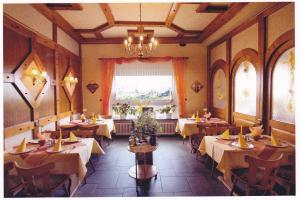 a restaurant with tables and chairs and a chandelier at Landgasthaus Blick ins Tal in Wißmannsdorf