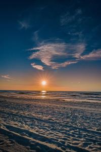 a beach with the sun rising over the ocean at Su Casa in Clearwater Beach