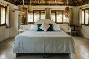 a bedroom with a large white bed with blue pillows at Mahayana Tulum Beach Homes in Tulum +122 photos