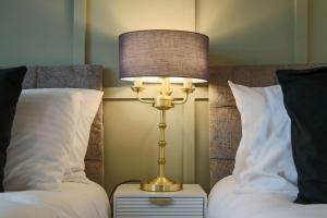 a lamp on a night stand next to two beds at Luxury 5 Bedroom 3 Bathroom House - Smart TVs with Sky and Netflix, Super Fast WiFi, Free Parking by Yoko Property in Milton Keynes