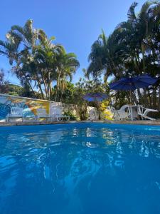 a large swimming pool with chairs and umbrellas at Pousada Catavento in Saquarema