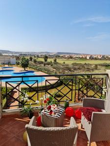 einen Balkon mit einem Tisch, Stühlen und einem Pool in der Unterkunft FamilyConfort Saidia in Saidia 