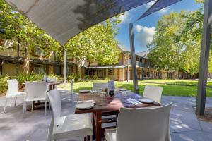 un patio con mesa de madera y sillas blancas en St Francis Winery en Old Reynella