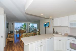 a kitchen with white cabinets and a living room at Ilikai Marina 382 Yacht Harbor View 1BR in Honolulu