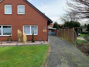 a brick house with a fence and a driveway at FEWO FloTi Ferienwohnung Augustfehn in Apen