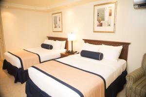 um quarto de hotel com duas camas e uma cadeira em Best Western El Dorado Panama Hotel na Cidade do Panamá