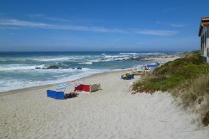 a beach with people sitting on the sand and the ocean at Holiday Home bei Viana do Castelo Carreco - PON03016-F in Carreço
