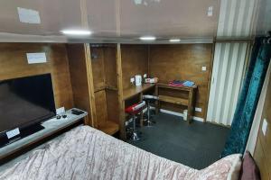 a room with a bed and a desk with a television at Adorable private suite with free street parking in Leicester