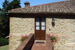 沃爾泰拉的住宿－Farmhouse stay Giulia Volterra，石头房子,带木门和鲜花