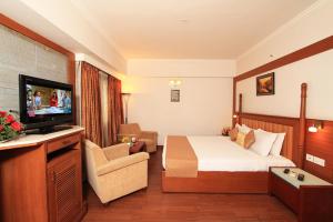 a hotel room with a bed and a flat screen tv at Parijatha Gateway in Bangalore