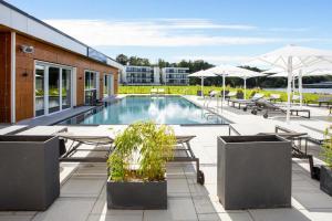 einen Pool mit Tischen, Stühlen und Sonnenschirmen in der Unterkunft Apartments in the MAREMÜRITZ Yachthafen Resort, Waren an der Müritz in Waren (Müritz)