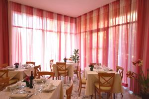 un comedor con mesas, sillas y ventanas en Hotel Paglierani, en San Mauro a Mare
