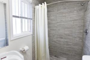 uma casa de banho com uma cortina de chuveiro e um lavatório em Holly Park Motel near LAX em Inglewood