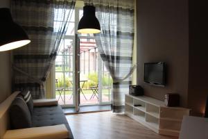 a living room with a couch and a tv and a window at Loft Niezapominajka w Tobaco Park in Łódź
